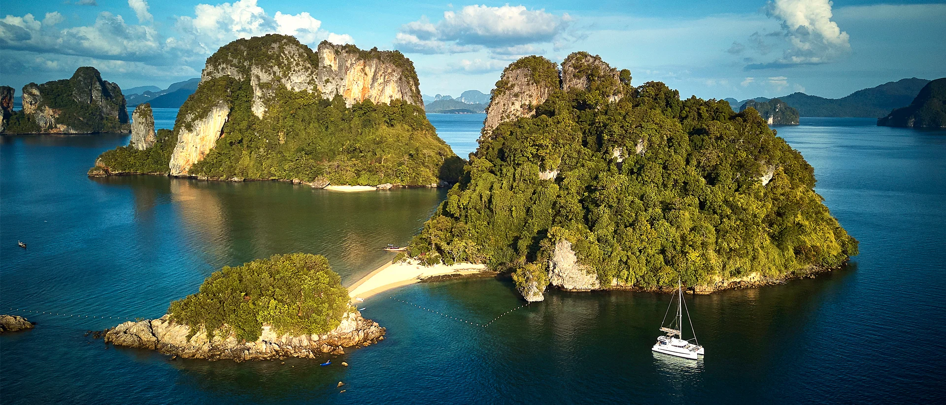 Bateaux voguant sur fond d'île et de rochers imposants en Thaïlande