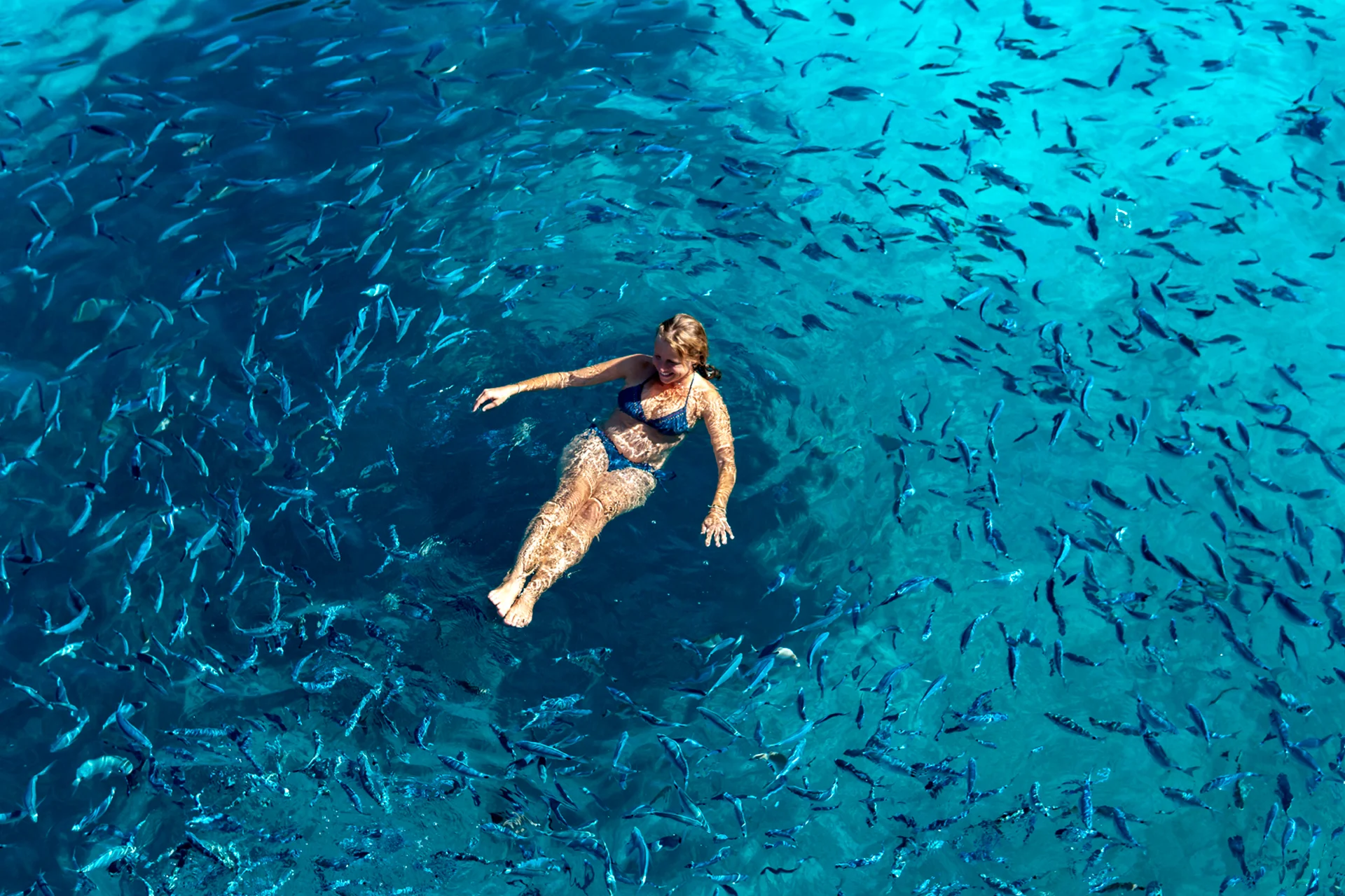 Korfu kvinna simmar i kristallklart hav på seglingssemester