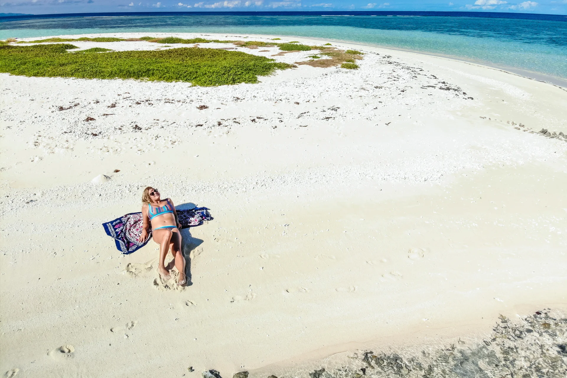 Donna che prende il sole in spiaggia durante le vacanze in barca a vela in Nuova Caledonia 