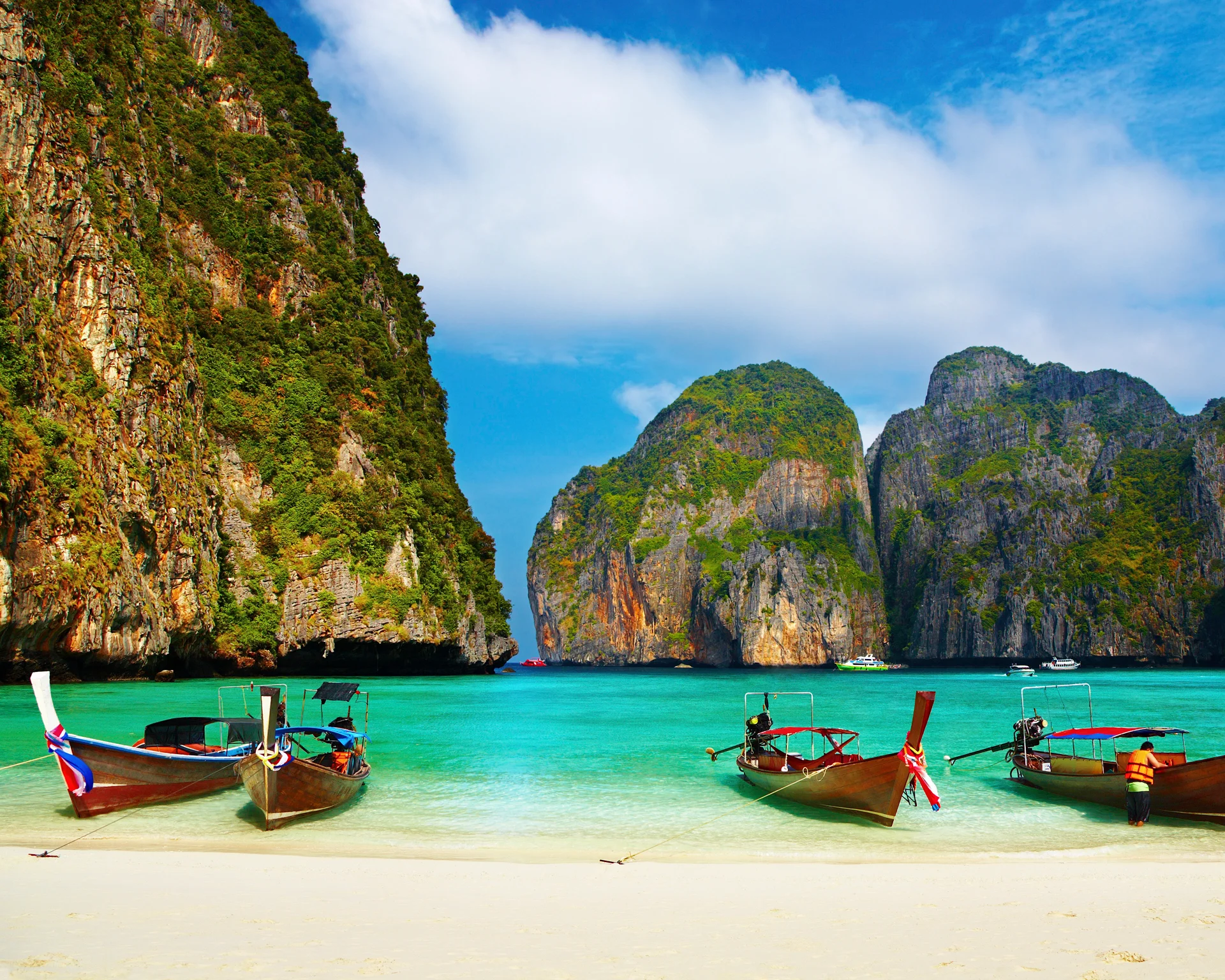 Thailand beach and boats towering rocks