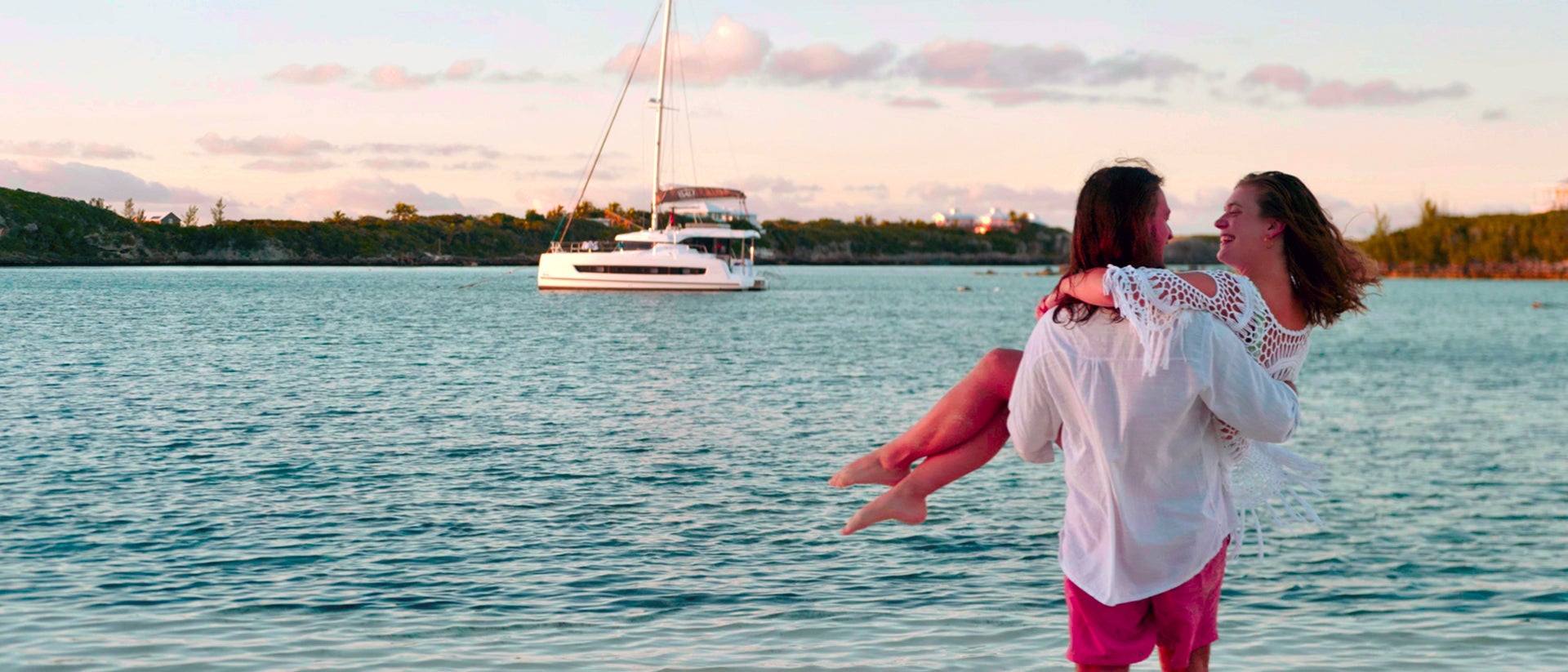 Coppia felice a bordo di un catamarano che si gode il tramonto alle Abaco