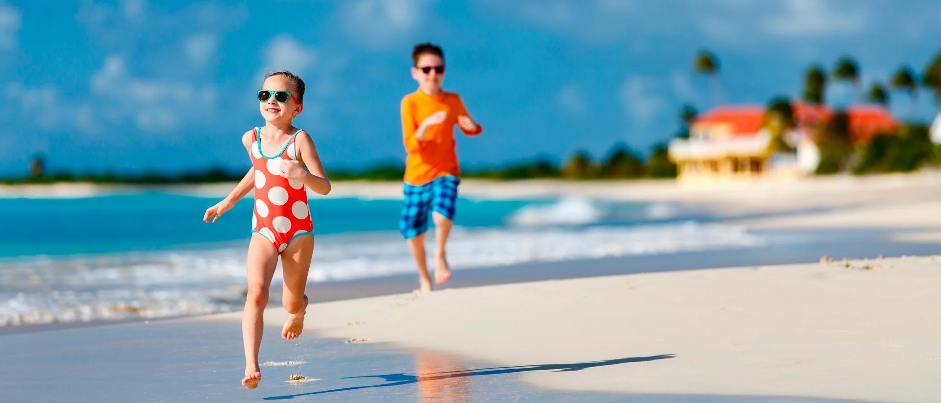 Antigua glad unge som springer på stranden familjesemester