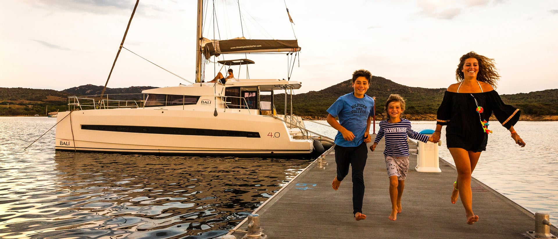 Familia feliz en un puerto de Córcega con un catamarán de alquiler
