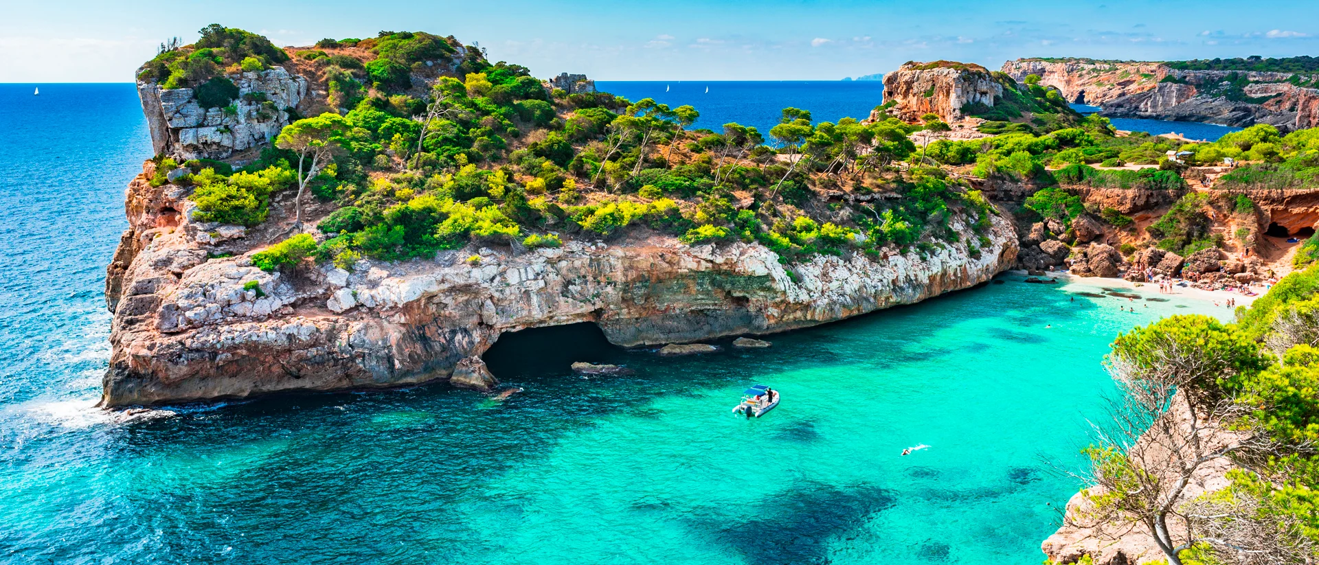 Embarcación de alquiler navegando por un paisaje natural de aguas azules por las islas Baleares