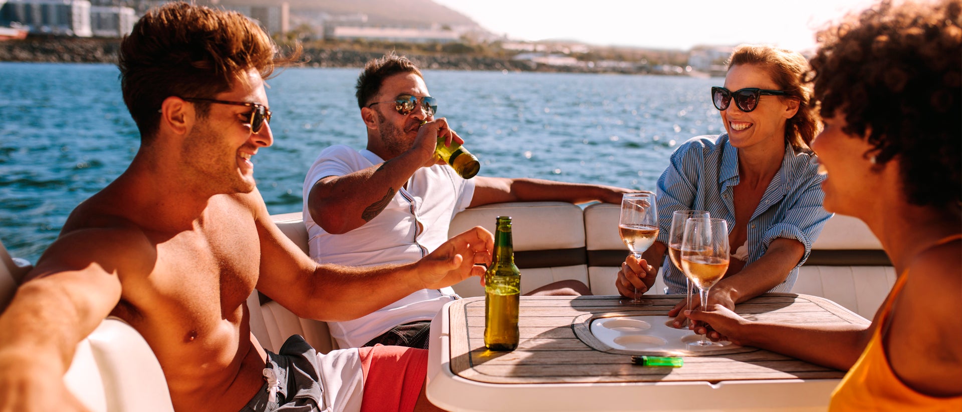 Amigos felices disfrutando de una bebida a bordo de un yate de alquiler en Cos