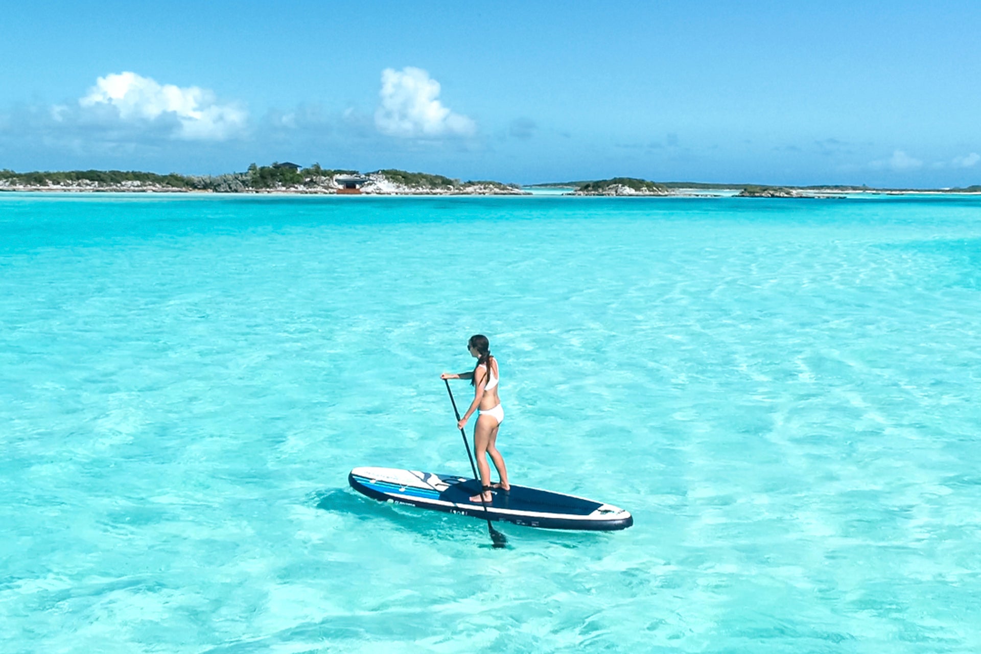 Mujer disfrutando de unas vacaciones en barco sobre la tabla de surf en Bahamas