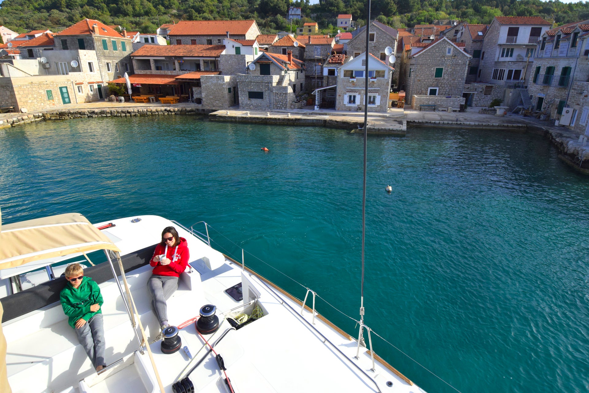 Familia disfrutando de unas vacaciones en un yate de alquiler junto a las casas del casco antiguo de Šibenik