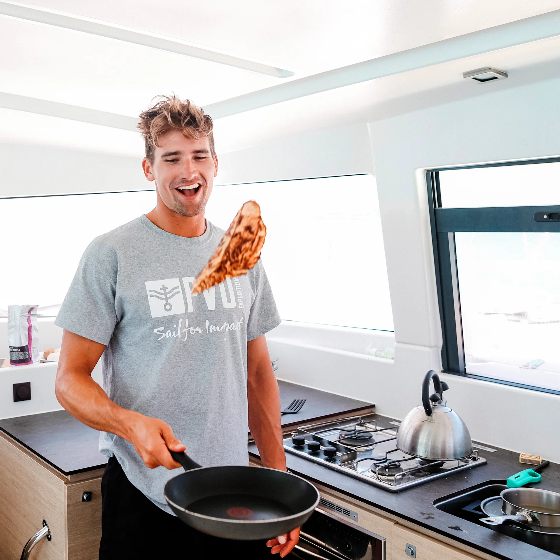Ragazzo che cucina in relax durante le vacanze in barca a vela a Lavrio