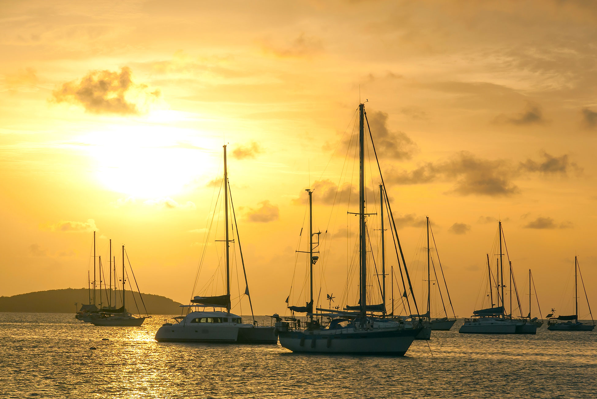 Moored sailing yachts and catamarans in St. Martin at sunset