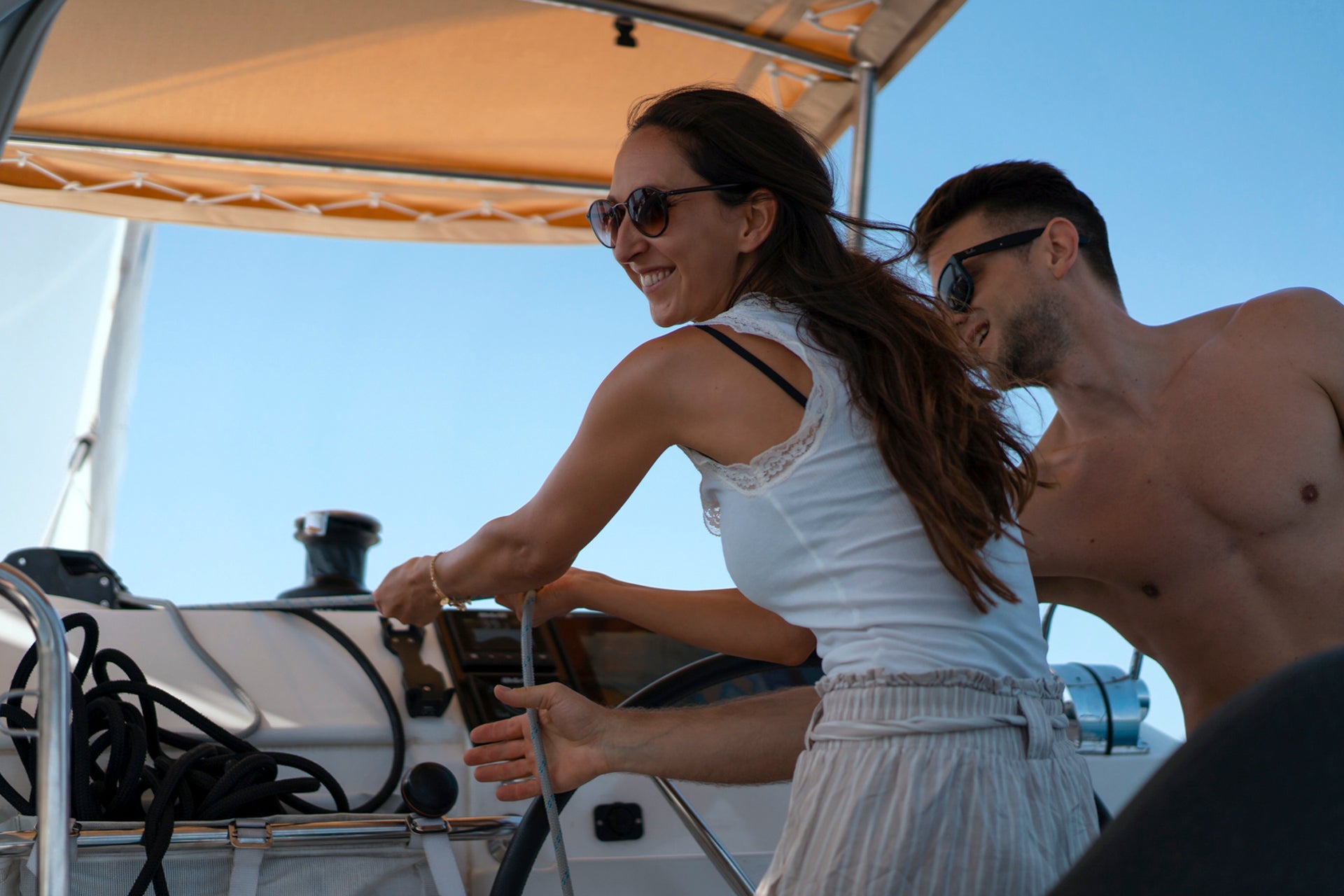 Pareja disfrutando y navegando en un yate de alquiler sin patrón