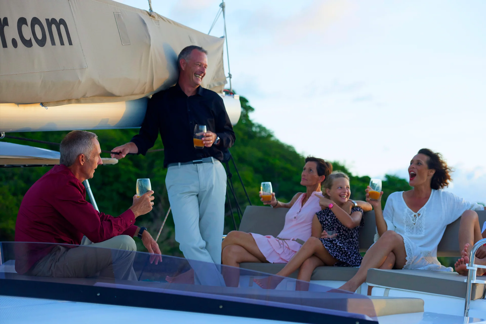 Vänner och familj njuter av semester i en båtcharter med full besättning i solnedgången