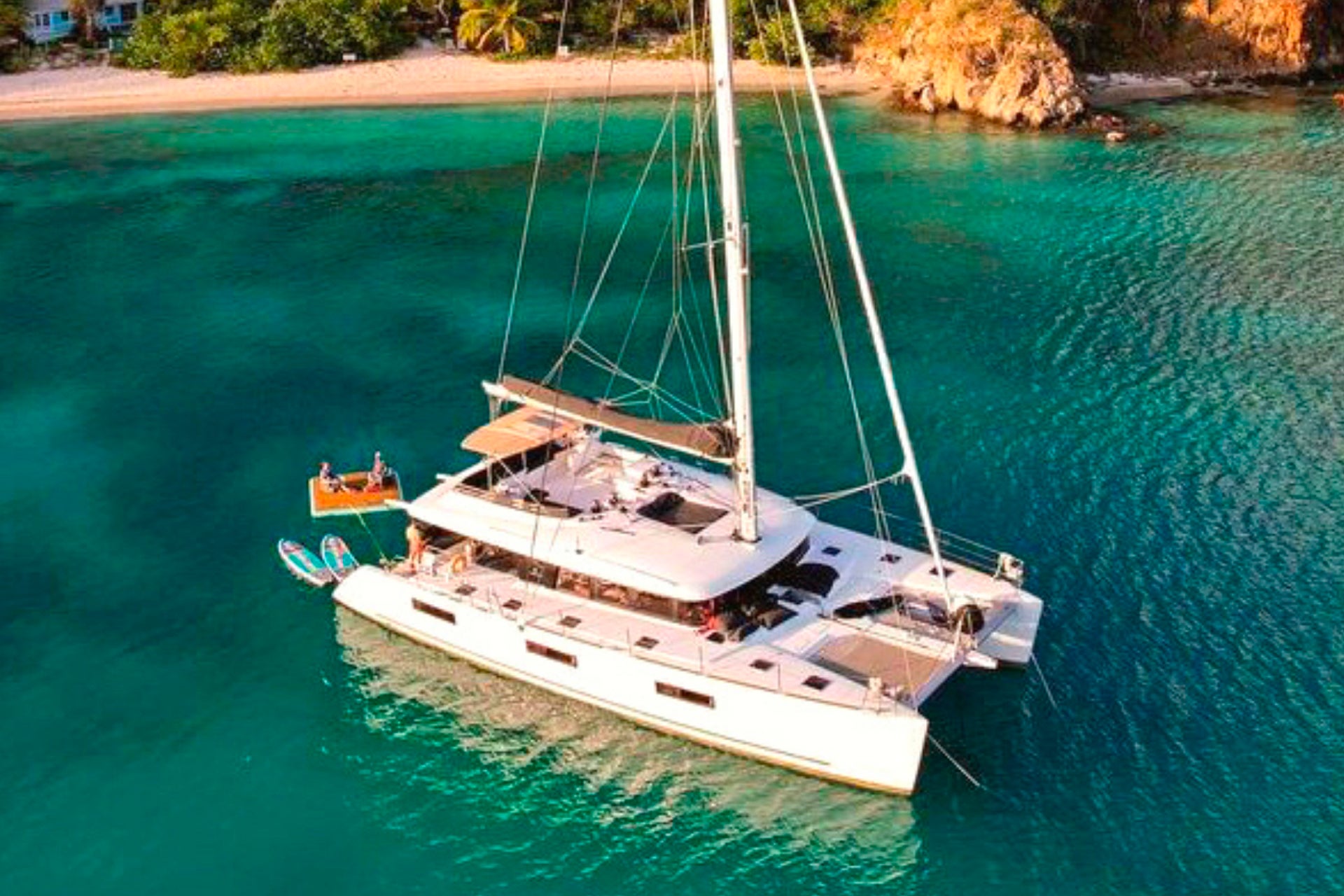 Catamaran avec équipage Premium ancré au large d'une plage superbe