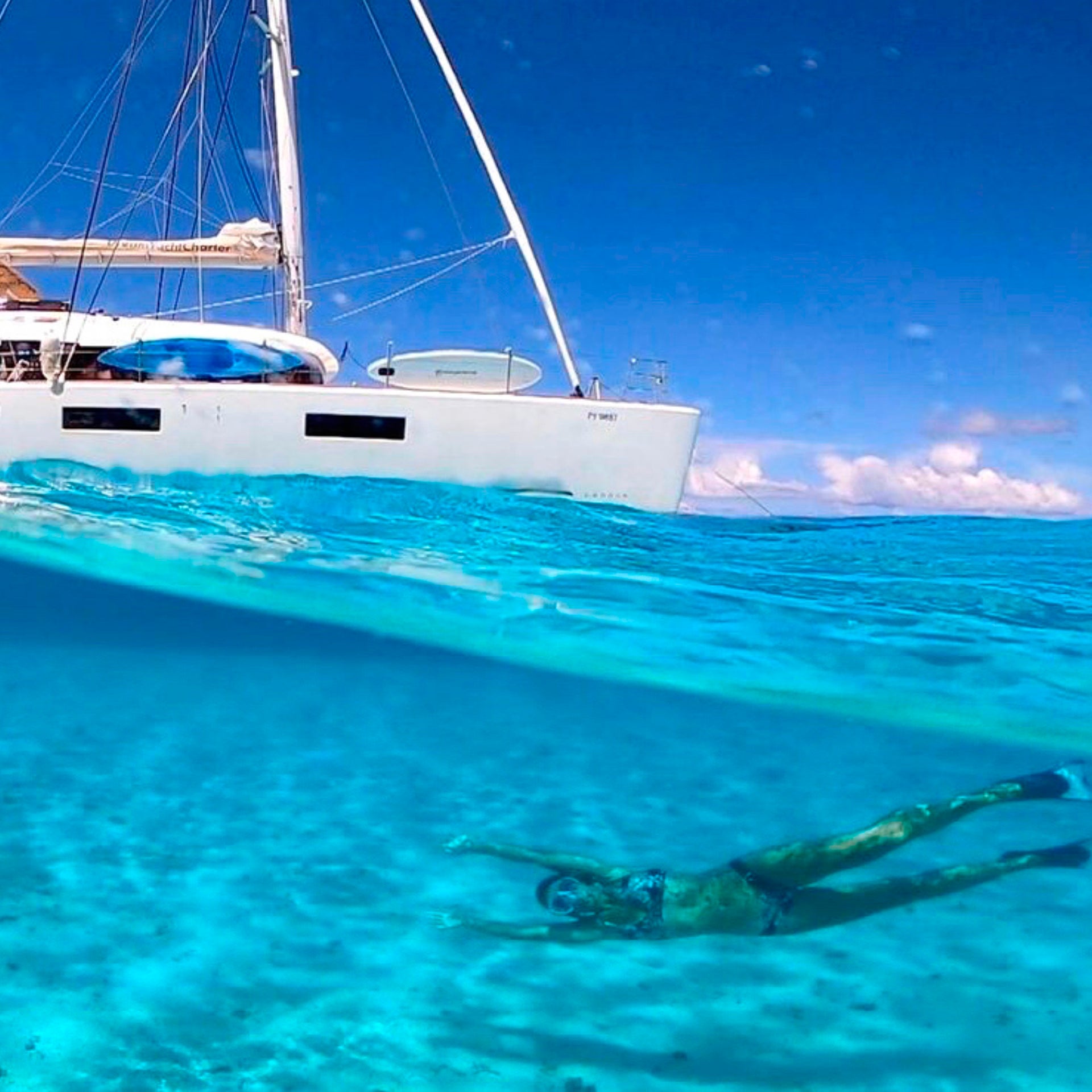 Tahiti catamaran jacht charter en gast zwemmend in kristalhelder water