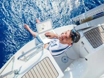 Man and computer on board of a yacht charter