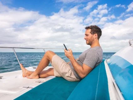 Man with mobile enjoying on board of a yacht charter