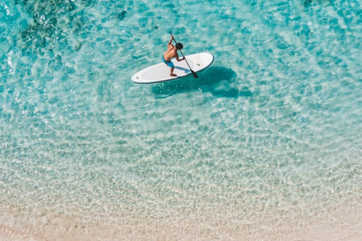 Uomo che fa paddlesurfing sulle acque blu