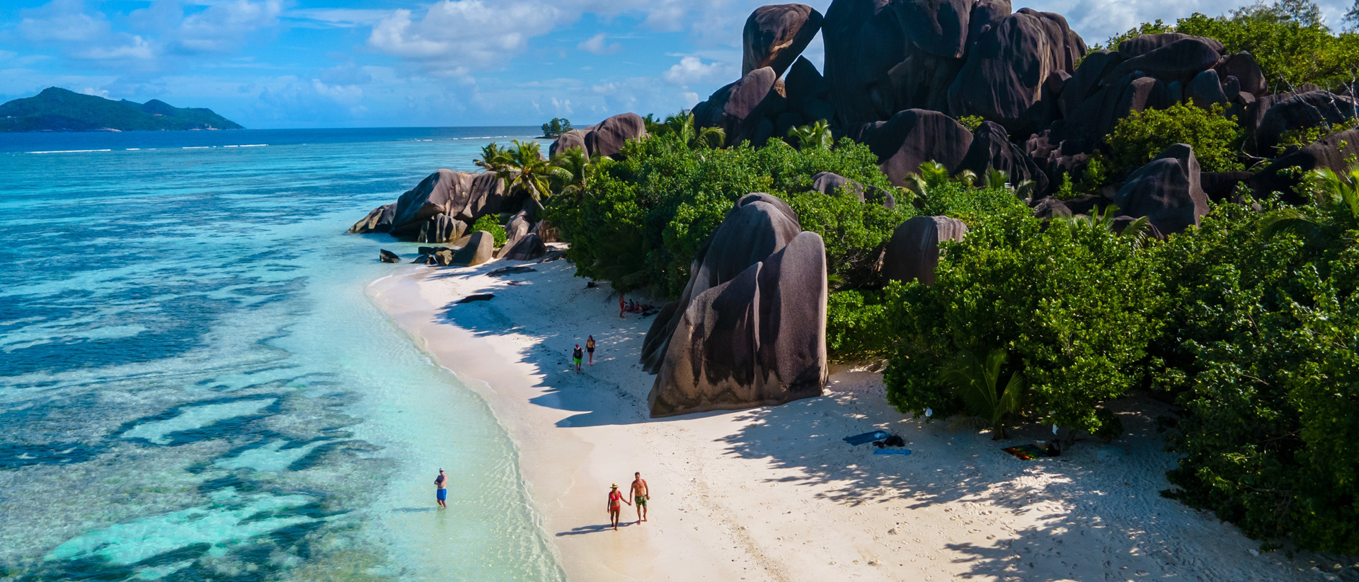 seychelles beach with couples walking using sustainable travel tips