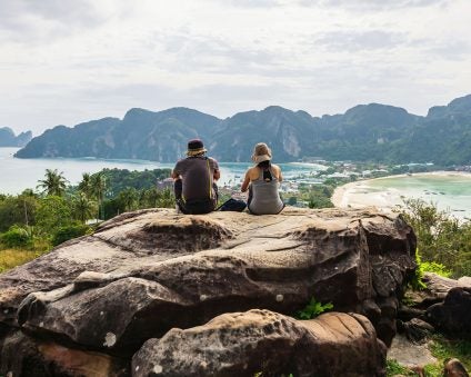 Hikers sitting on an overlook while hiking on Phi Phi Don, Thailand
