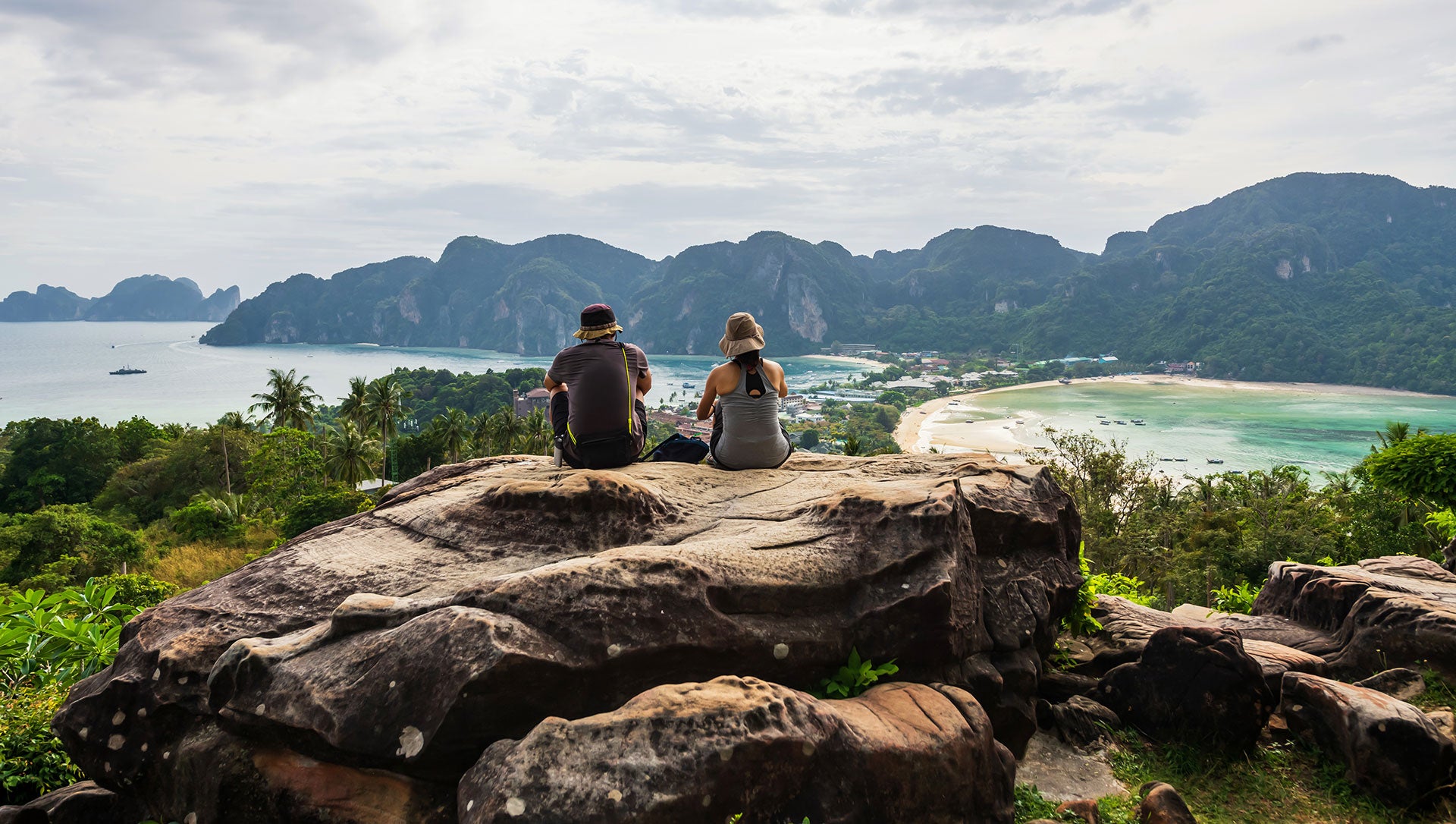 Hikers sitting on an overlook while hiking on Phi Phi Don, Thailand