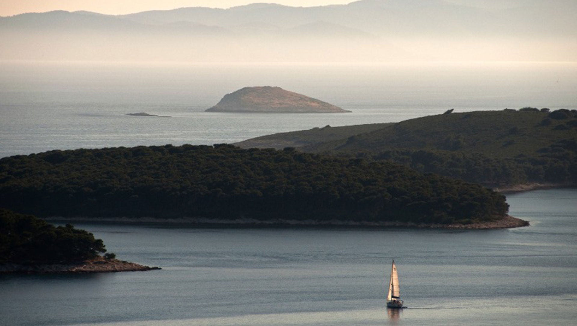 Pakleni Islands at sunrise over the water.