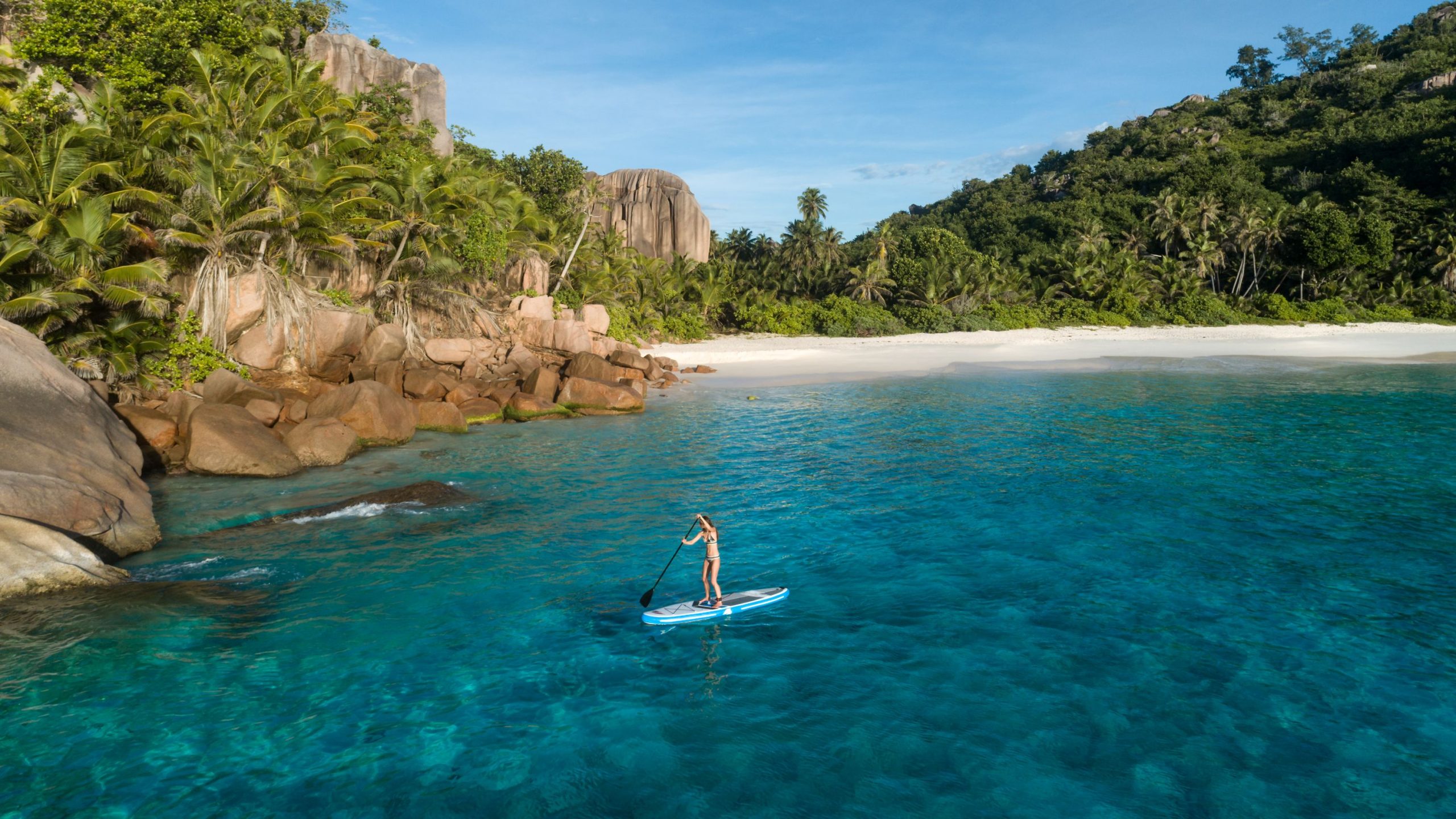 Woman on a paddleboard in the Seychelles on crystal clear.
