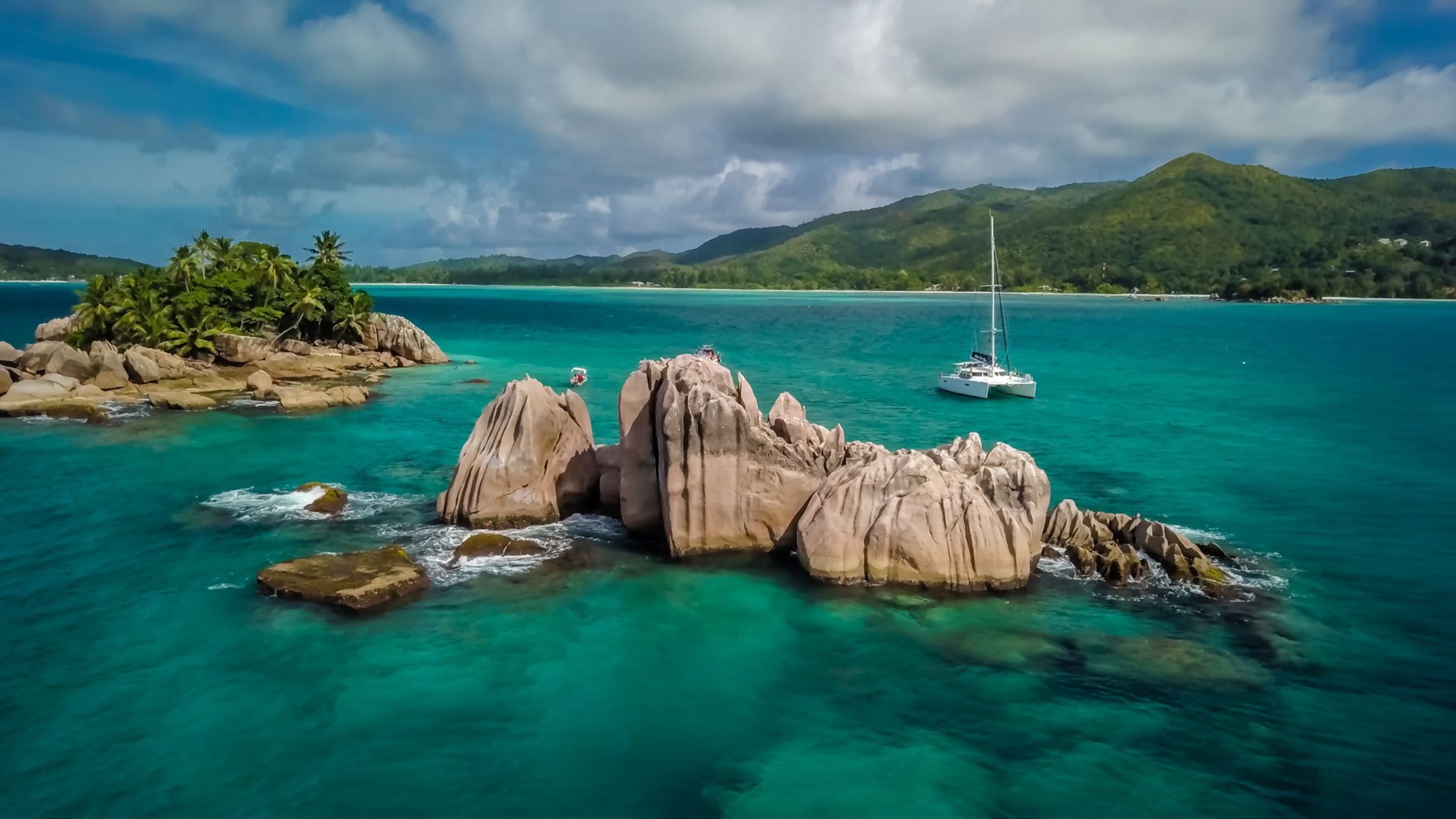 A sailing catamaran in the beautiful Seychelles, boulders rising out of the sea